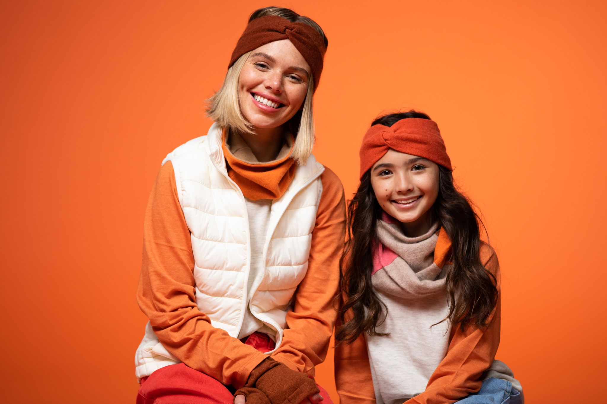 Female and girl models posing for the camera smiling against an orange backdrop