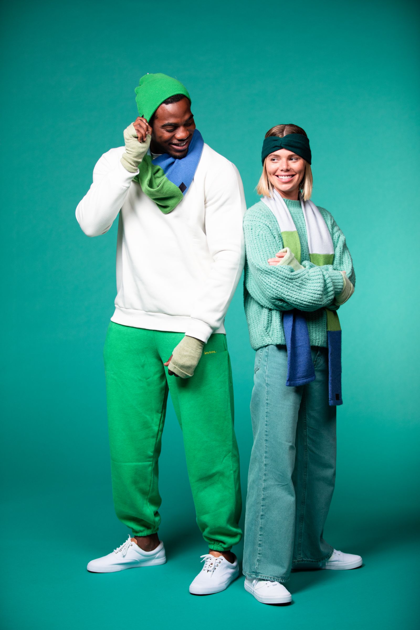 African American Male and female models posing for the camera smiling against a teal backdrop