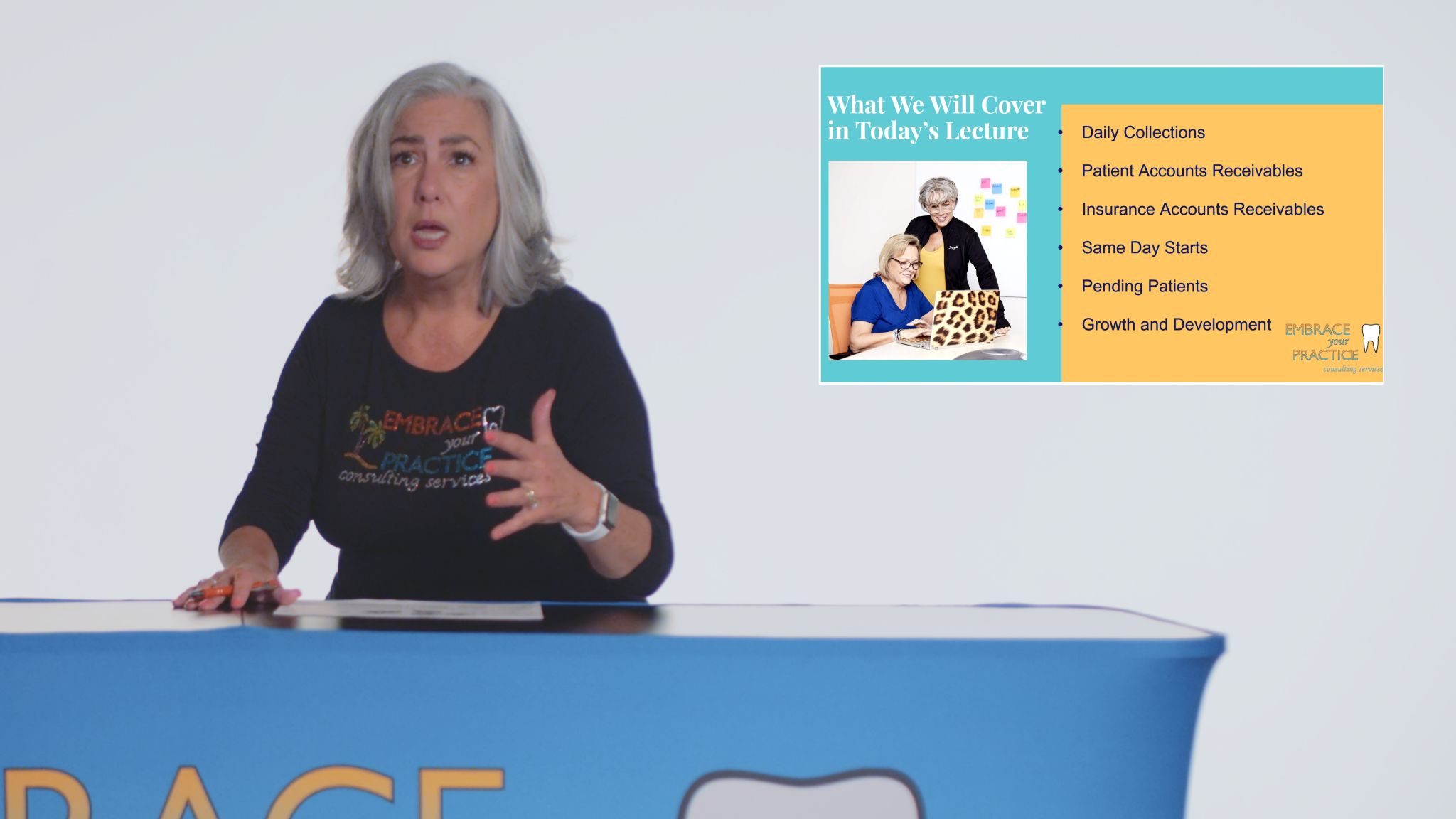 Woman with gray hair talking wearing black shirt with colorful logo and What We Will Cover in Today's Lecture insert