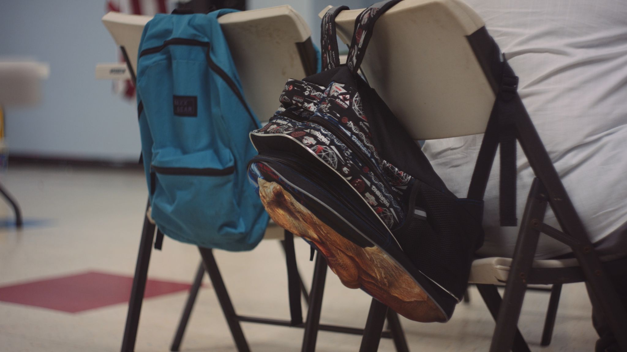 Closeup of backpacks hanging from the back of chairs