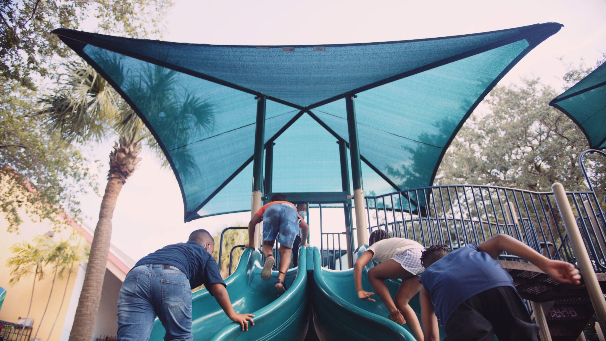 Four kids playing on a slide on a playground