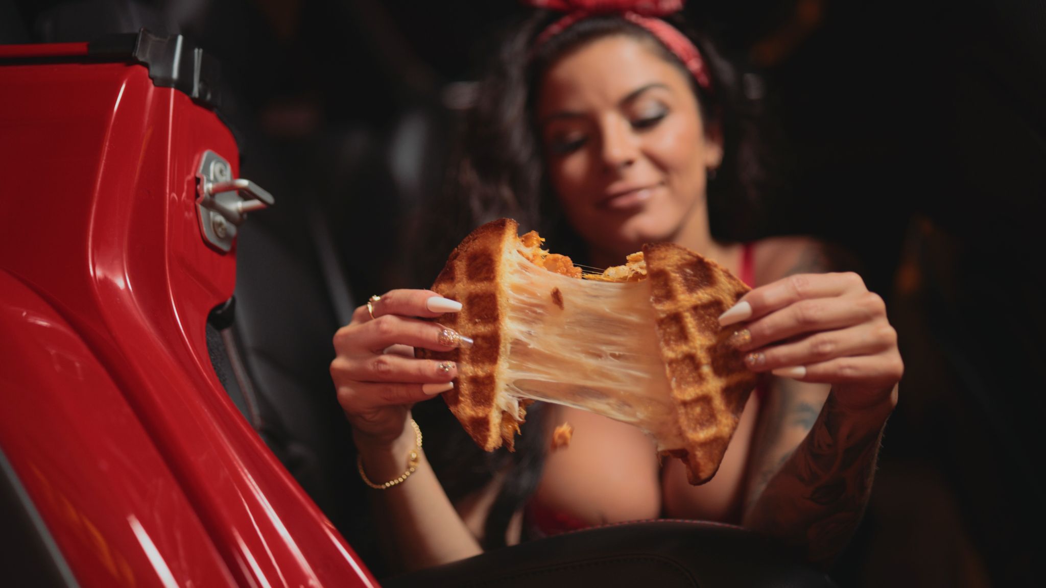 Woman with long brown hair spreading a grilled cheese sandwich she is holding in front of her