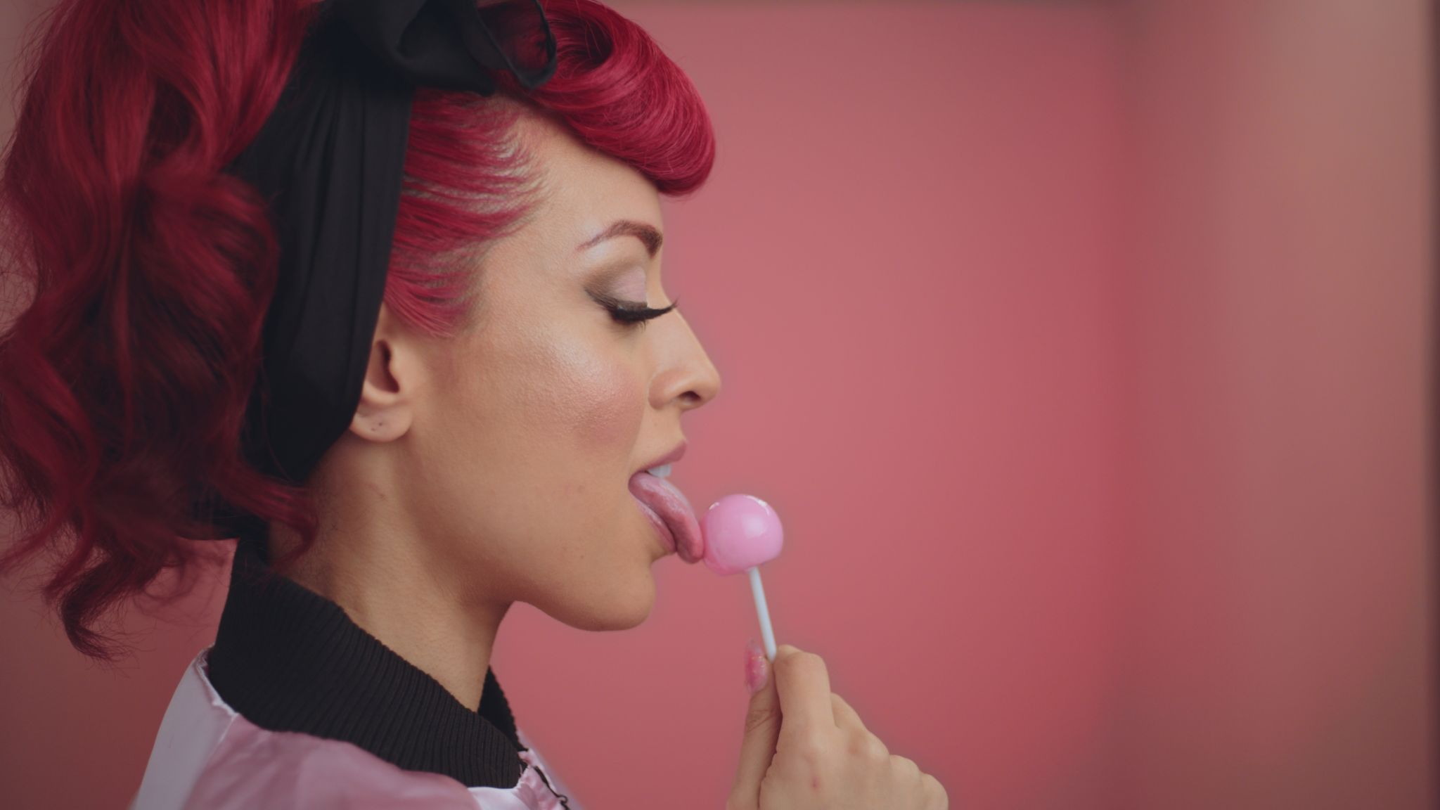 Pretty Vulgar Side view of Marielle with red hair licking a pink lollypop with eyes closed