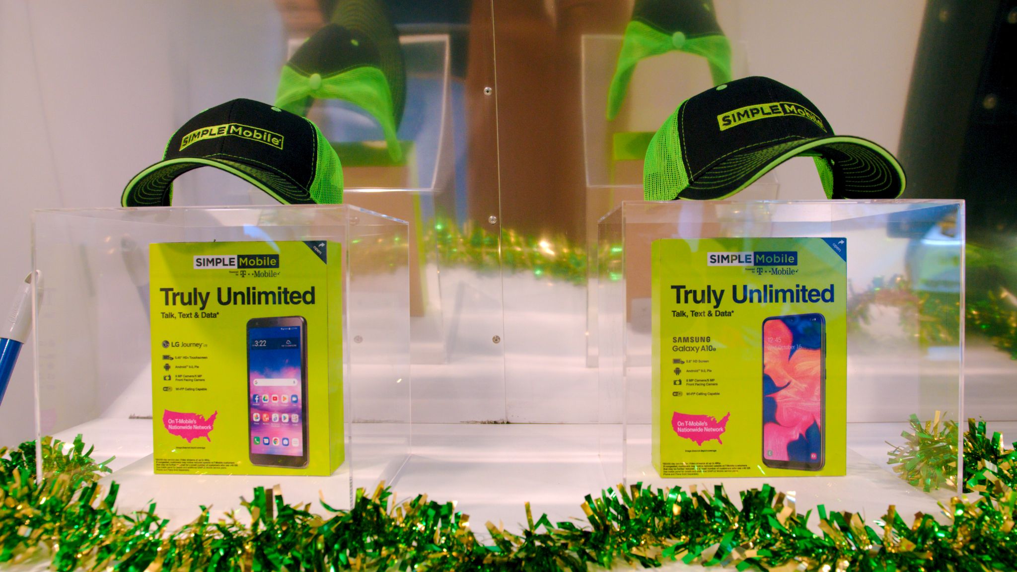 Two phone cases on display in glass with store caps with logos resting on top
