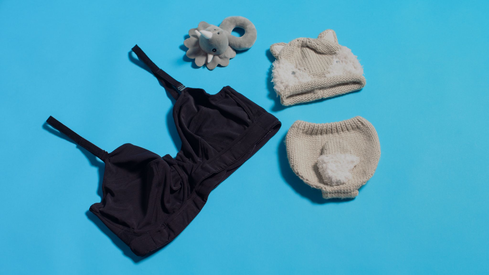 JENNAbra Product Flatlays Black bra on display with two gray knitted hats and gray plush toy