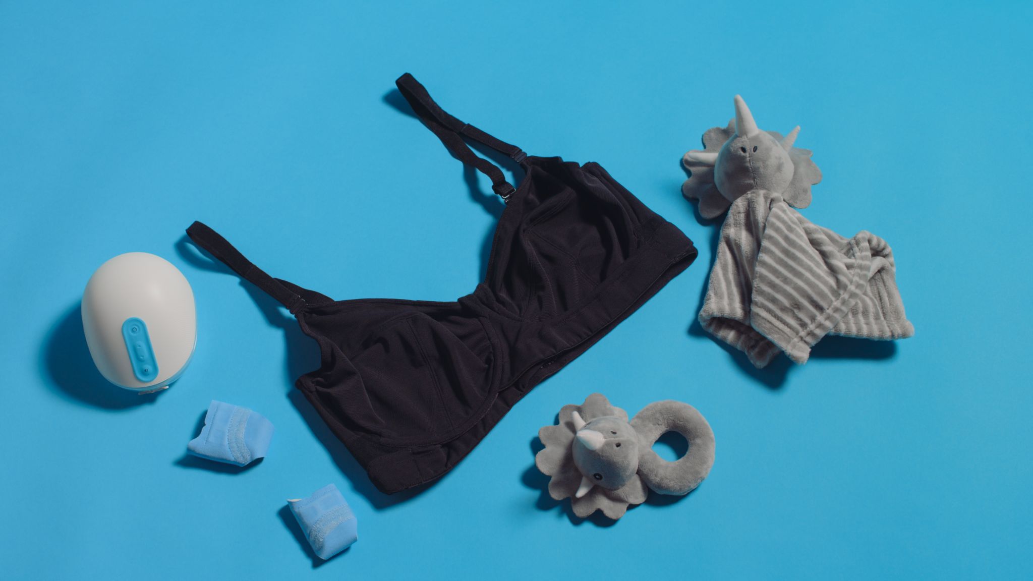 JENNAbra Product Flatlays Black bra on display with breastfeeding devices and two stuffed animal elephant toys