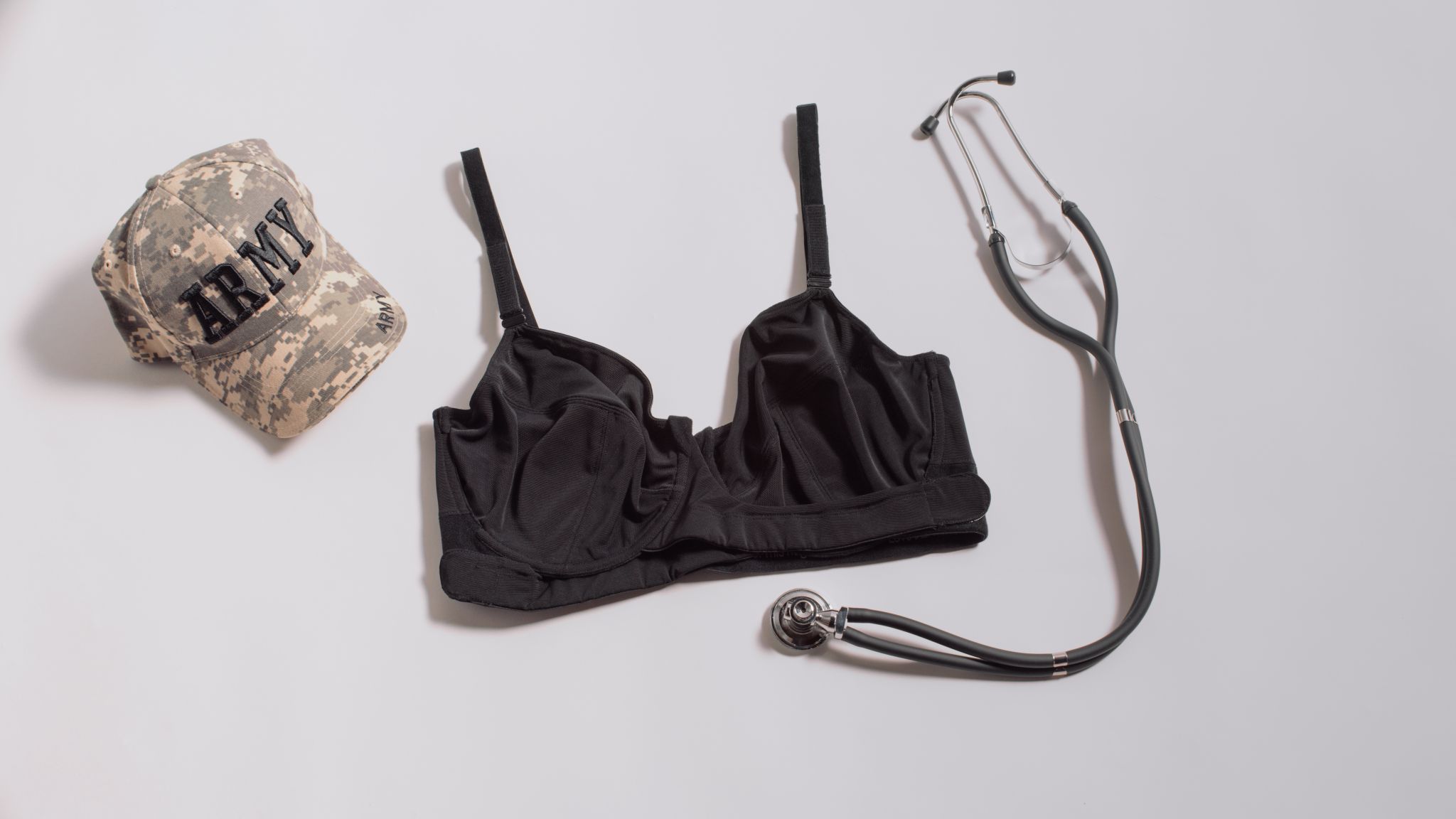 JENNAbra Product Flatlays Black bra on display with stethoscope and modern camoflauge Army hat