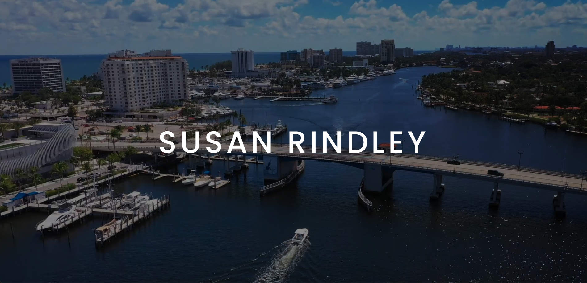 IU Susan Rindley Cover with white logo against a backdrop of boat cruising in a canal by a city towards a bridge with other boats docked in a harbor nearby