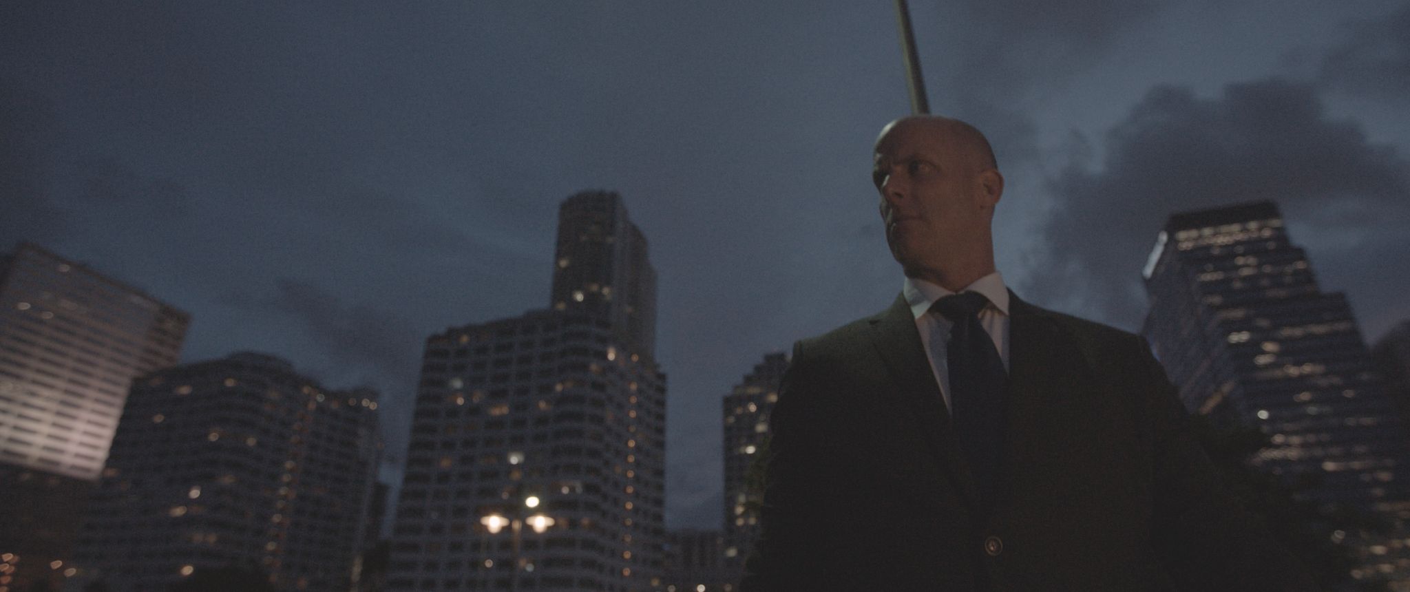 View looking up at a man dressed in a suit with the city in the background