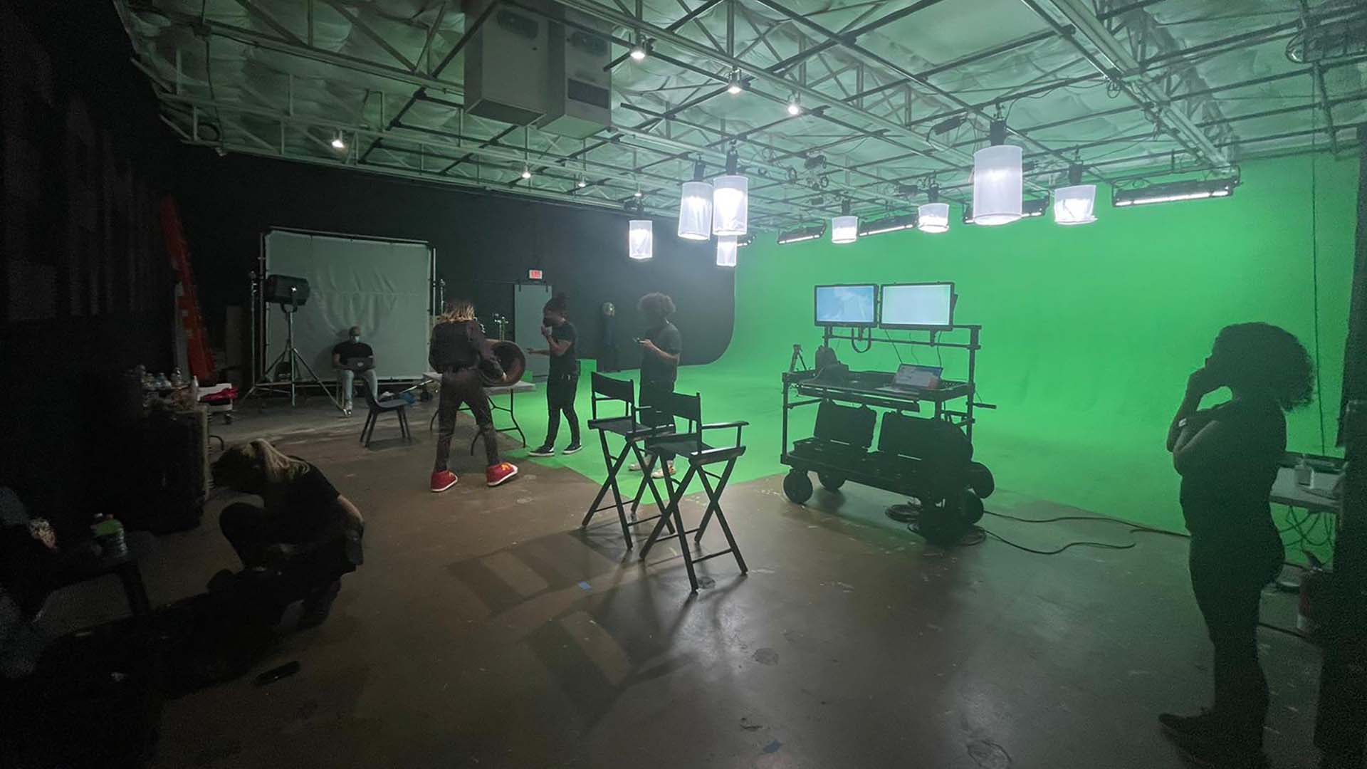 Crew working on a production inside a large green screen studio