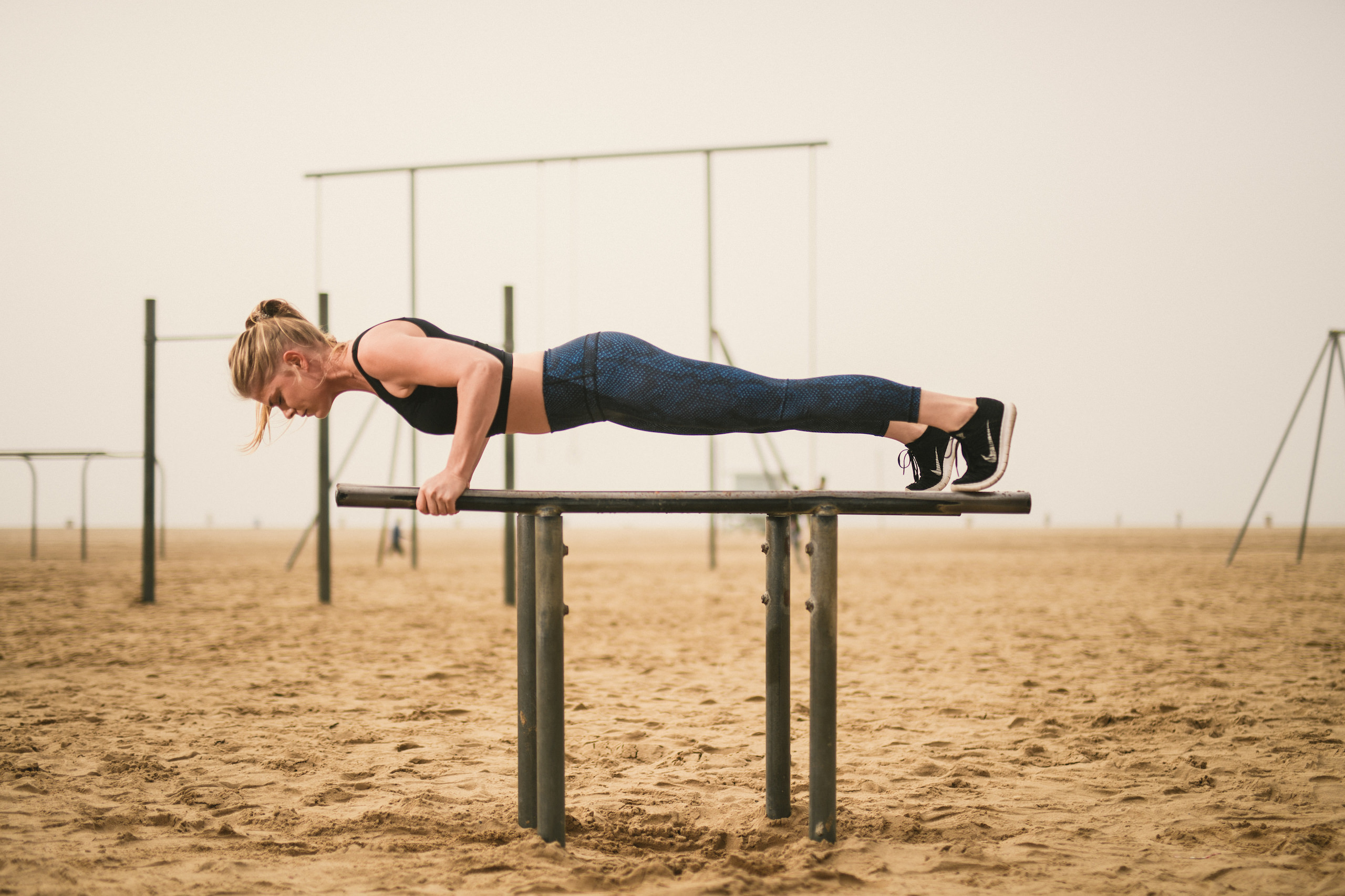 Health and Fitness Marketing JSM Side profile of woman doing a plank on metal parallel bars