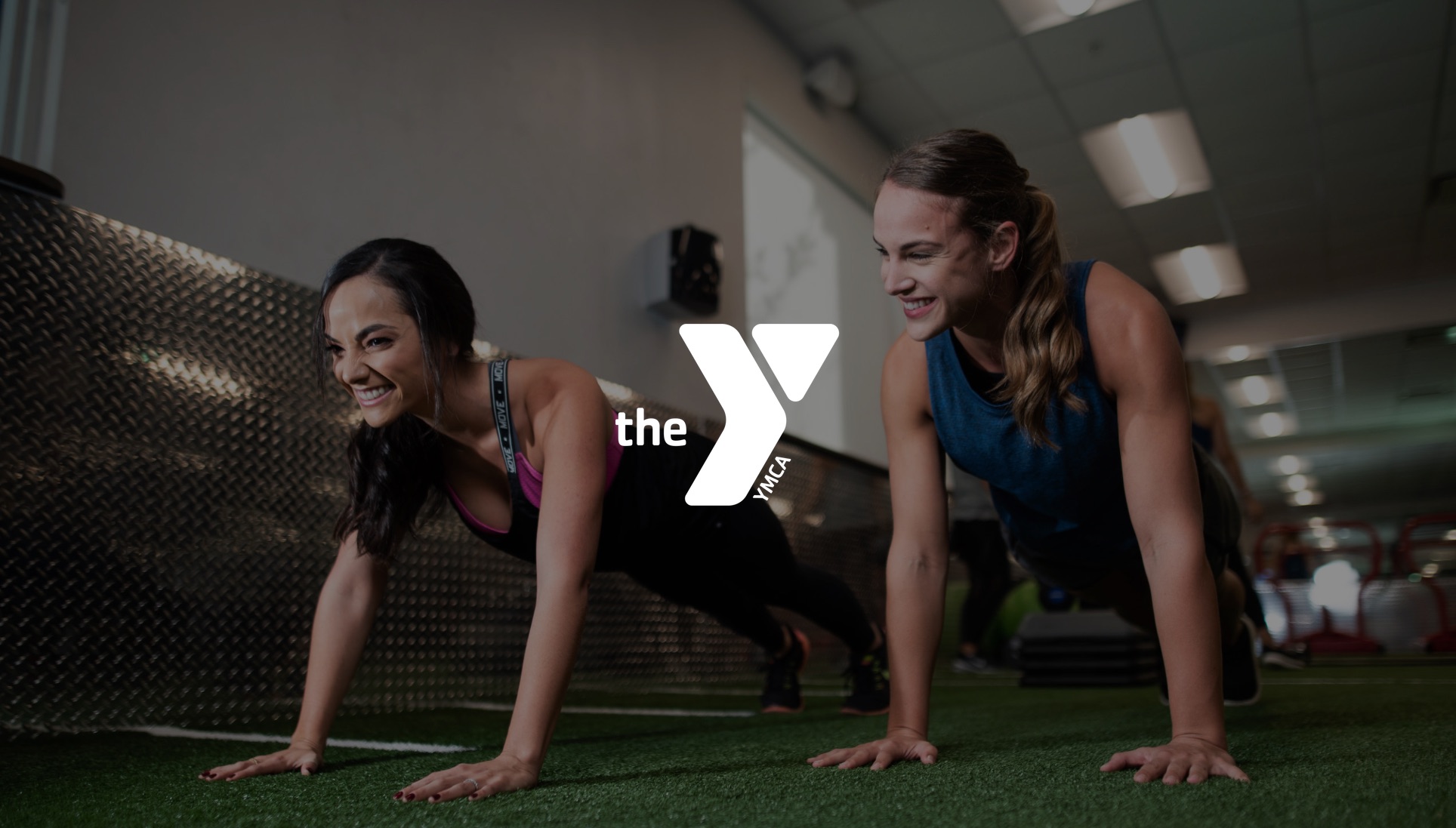 IU C&I Studios Page YMCA Two woman doing planks on the green turf in a gym