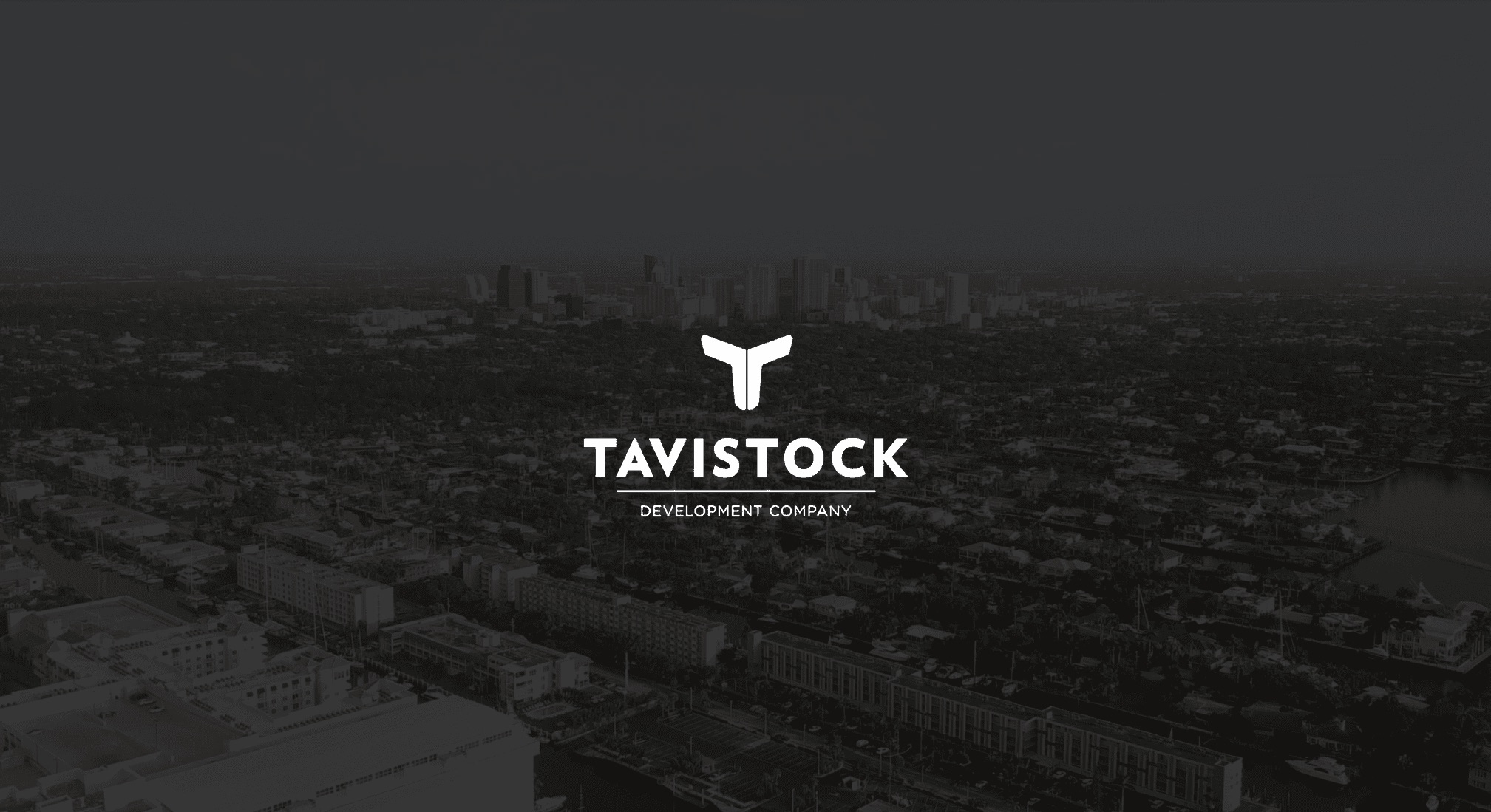 IU C&I Studios Page White Tavistock Development Company logo against a dimmed overhead view of the city