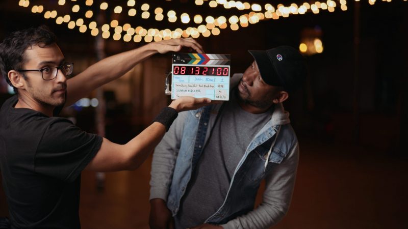 Steven Perez Grip Using A Clapboard In Front Of Joshua Who Is Looking On