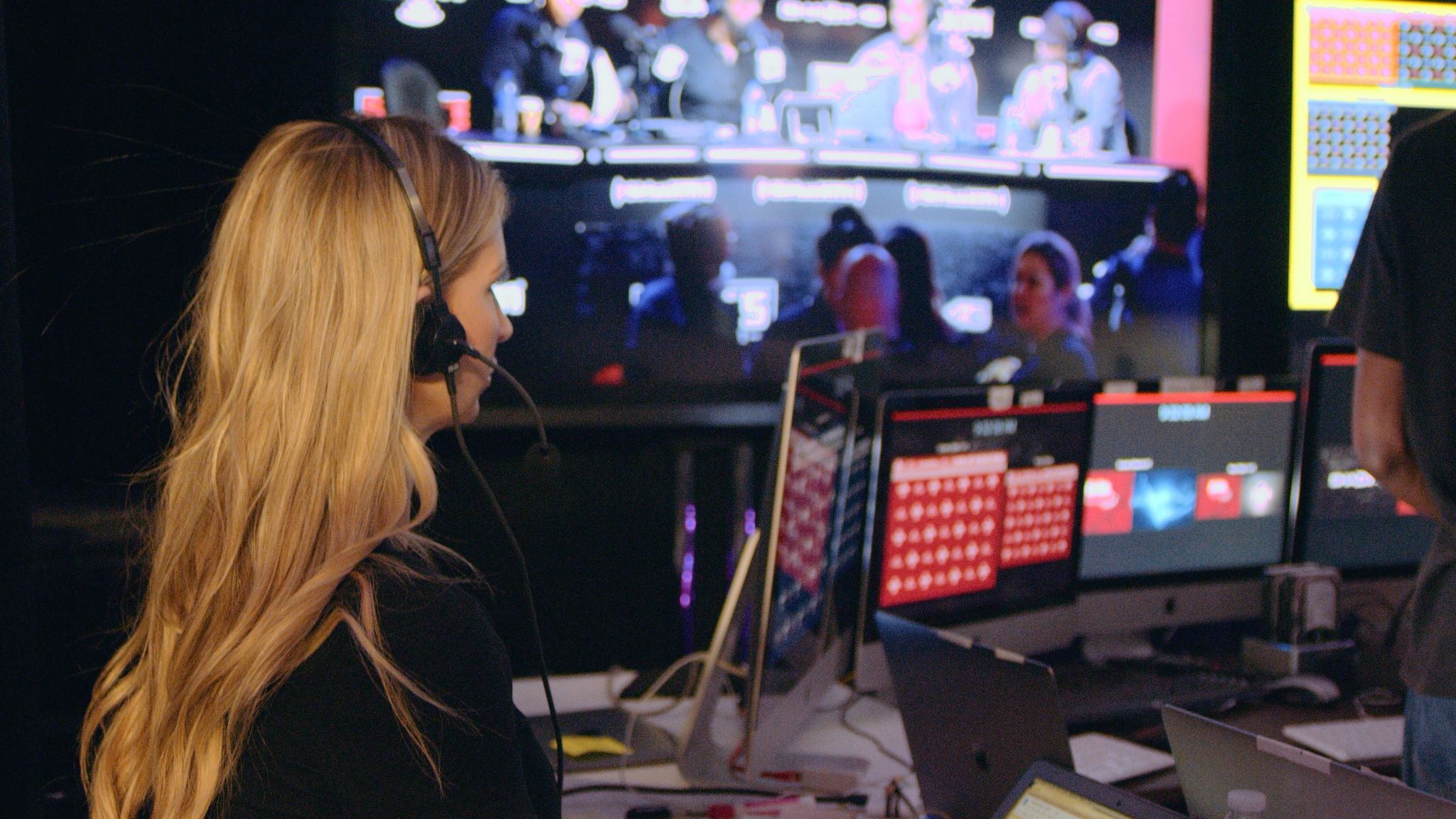 What to Consider in Event Production in a Post COVID world focus on video streaming Side profile of woman with long blond hair wearing a headset by video bank