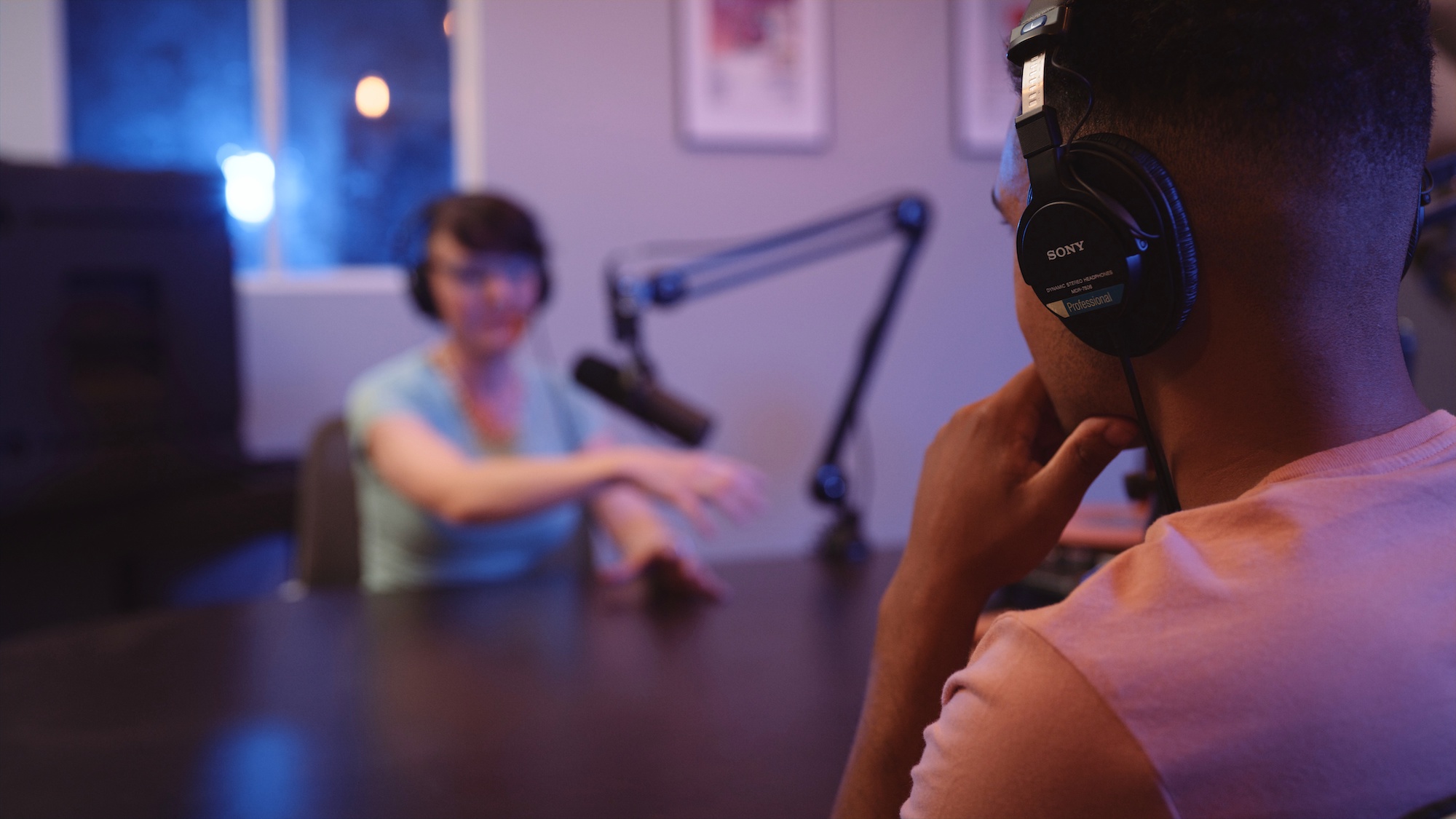 Fully Equipped Podcast Studio View from behind of man wearing black headphones being interviewed by a woman also wearing headphones