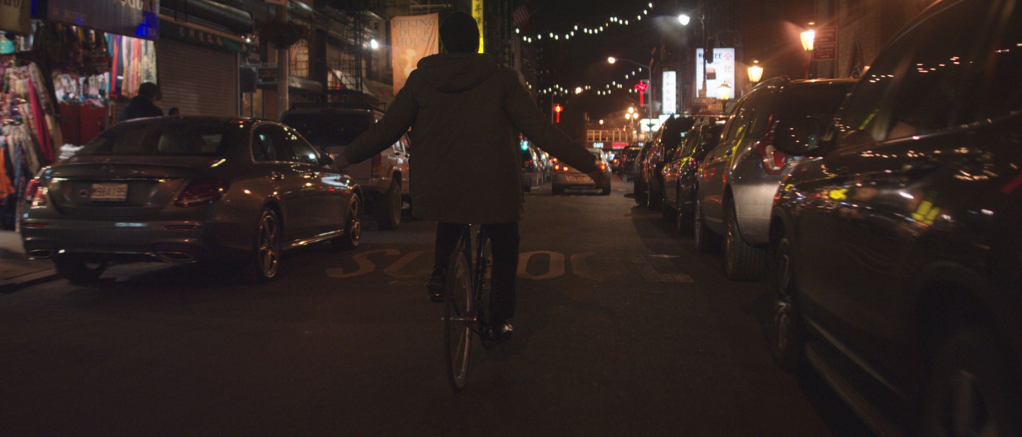 How CI Studios Uses Video and Film to Tell Great Stories and Why We Love Storytelling View from behind of a man biking through the street lined with cars at night with arms outstretched