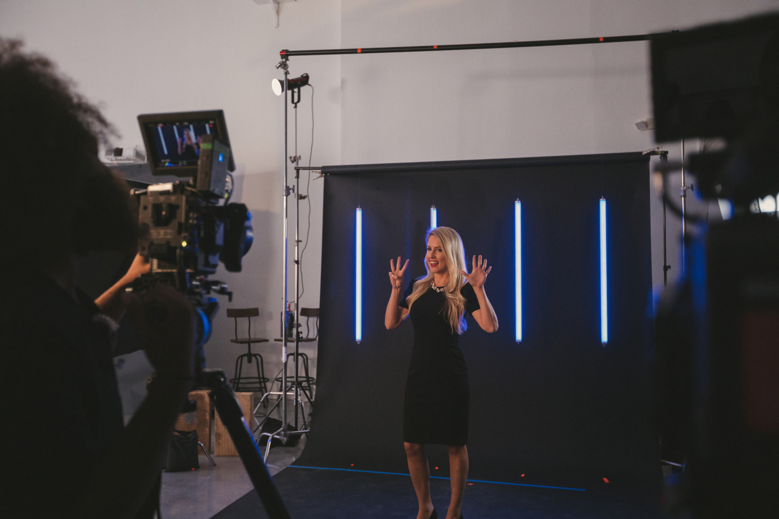What Your Brand Video Might be Missing Woman with long blond hair being filmed holding her hands up signaling number eight