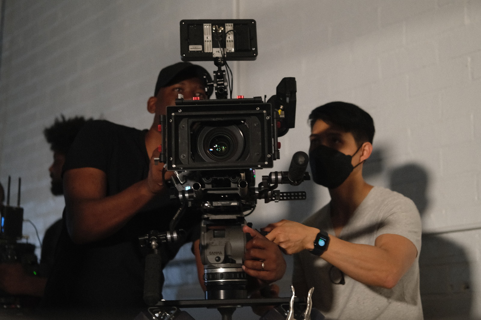 What makes a good producer Closeup of Joshua wearing a black cap and another male crew member wearing a black mask using a video camera