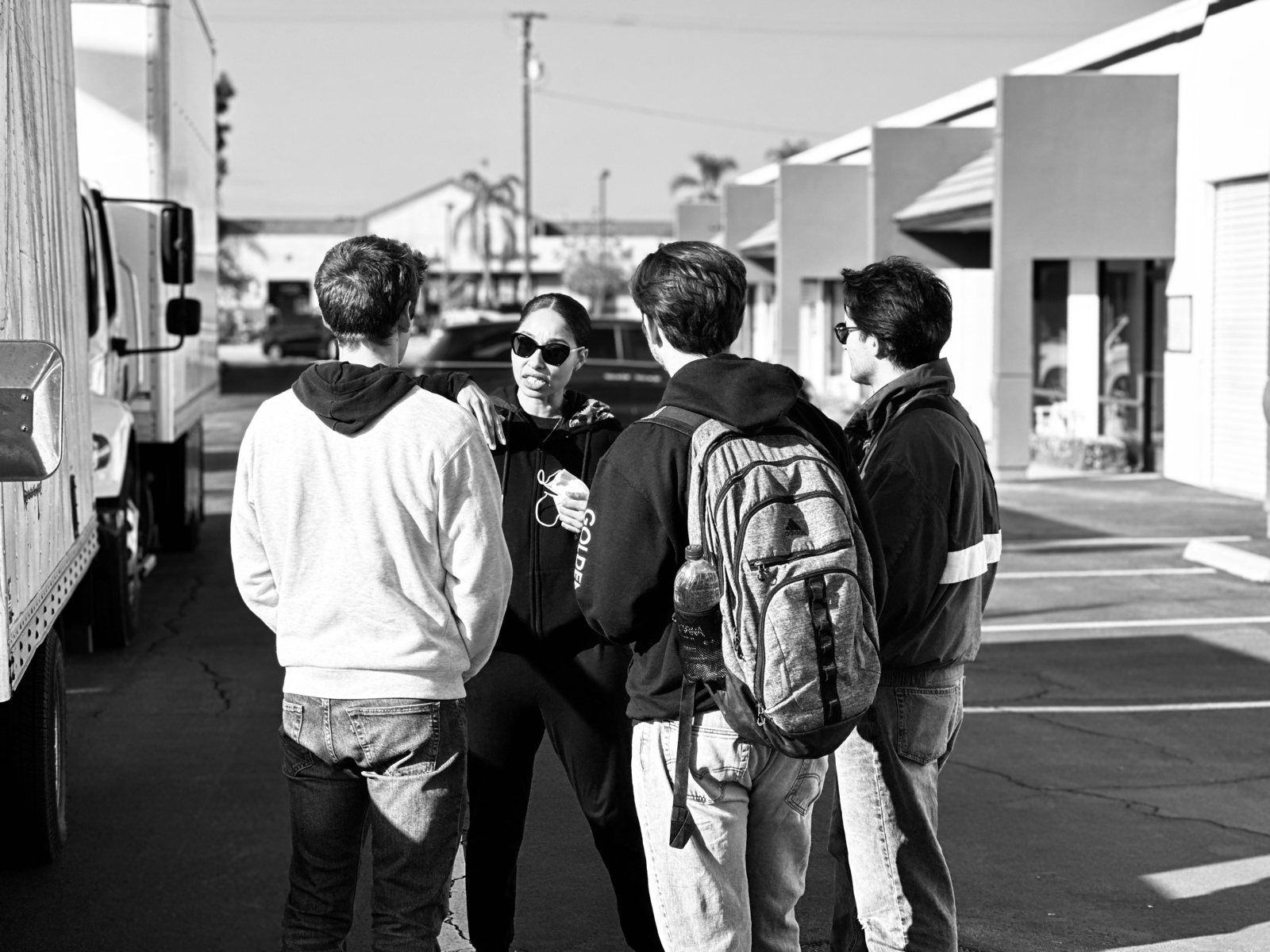 Black and white of a woman talking to three men on a parking lot