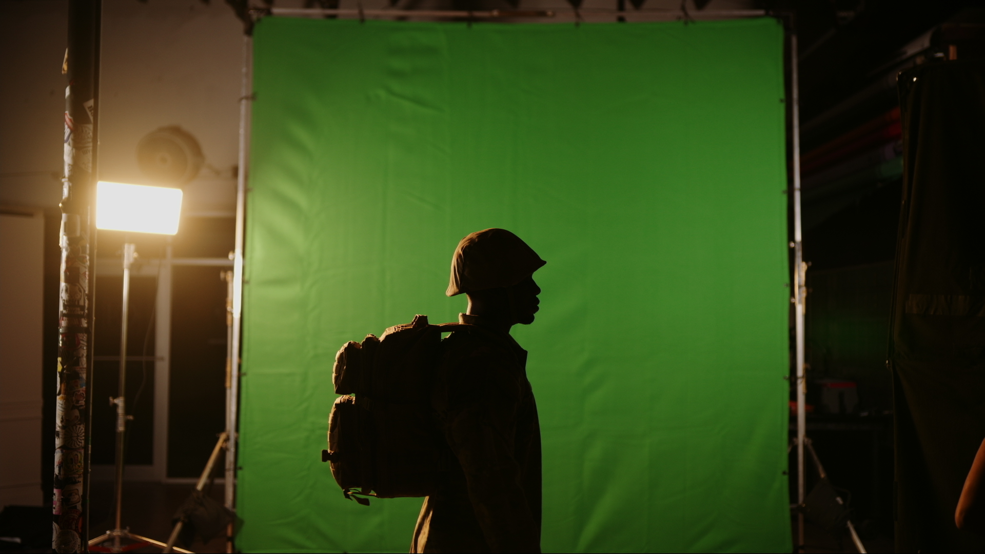 Tips for Shooting Video on Green Screen Side profile silhouette of a soldier wearing gear and a backpack standing in front of a green backdrop