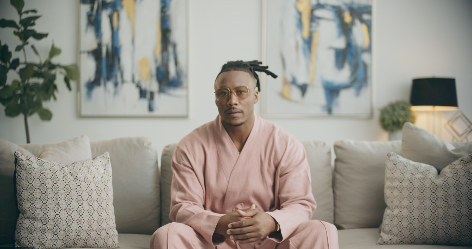 Key Elements to capturing docustyle interviews African American man wearing a pink outfit sitting on a couch posing or the camera