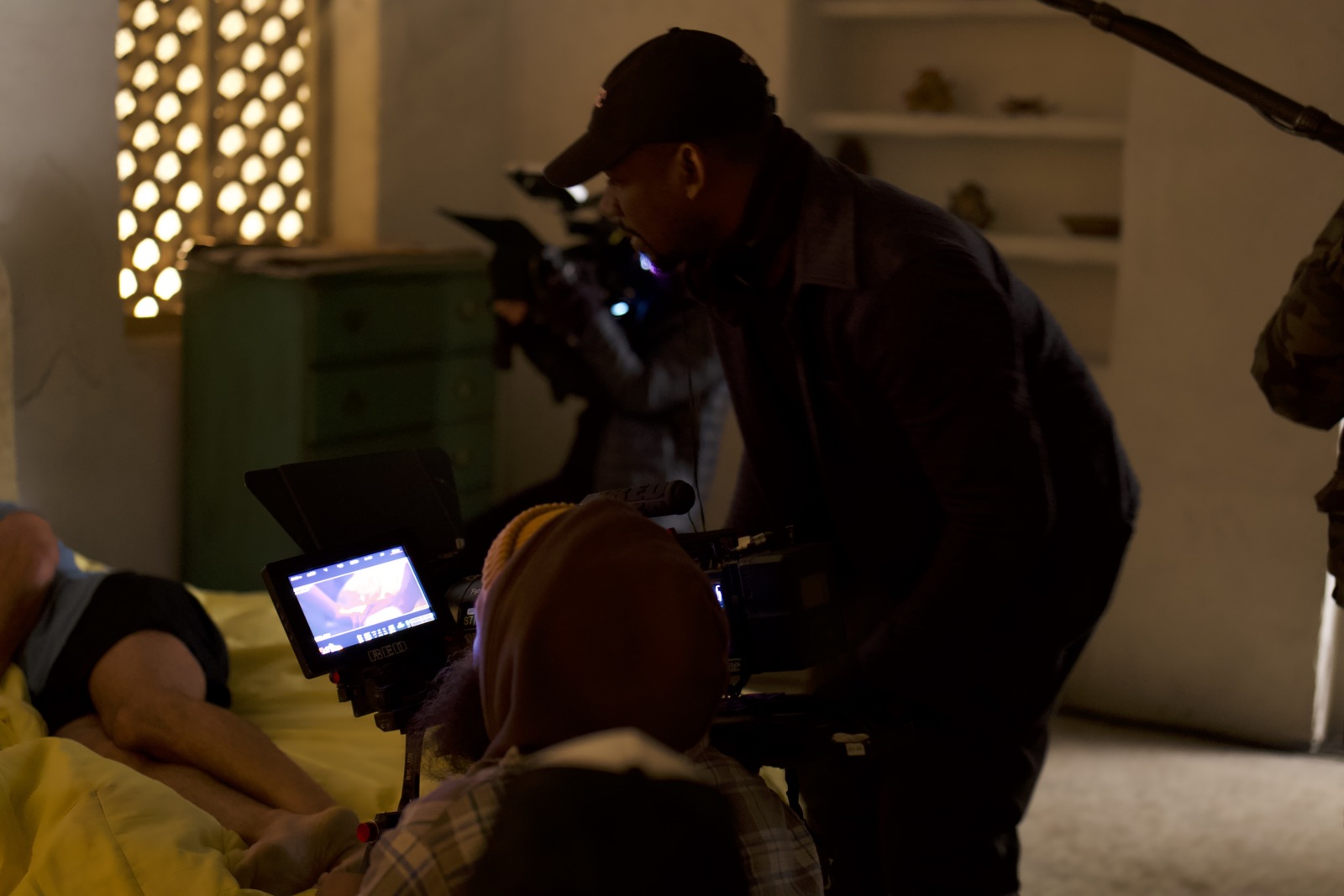 Side profile of Joshua wearing a black ball cap looking at video camera video display on set during a shoot