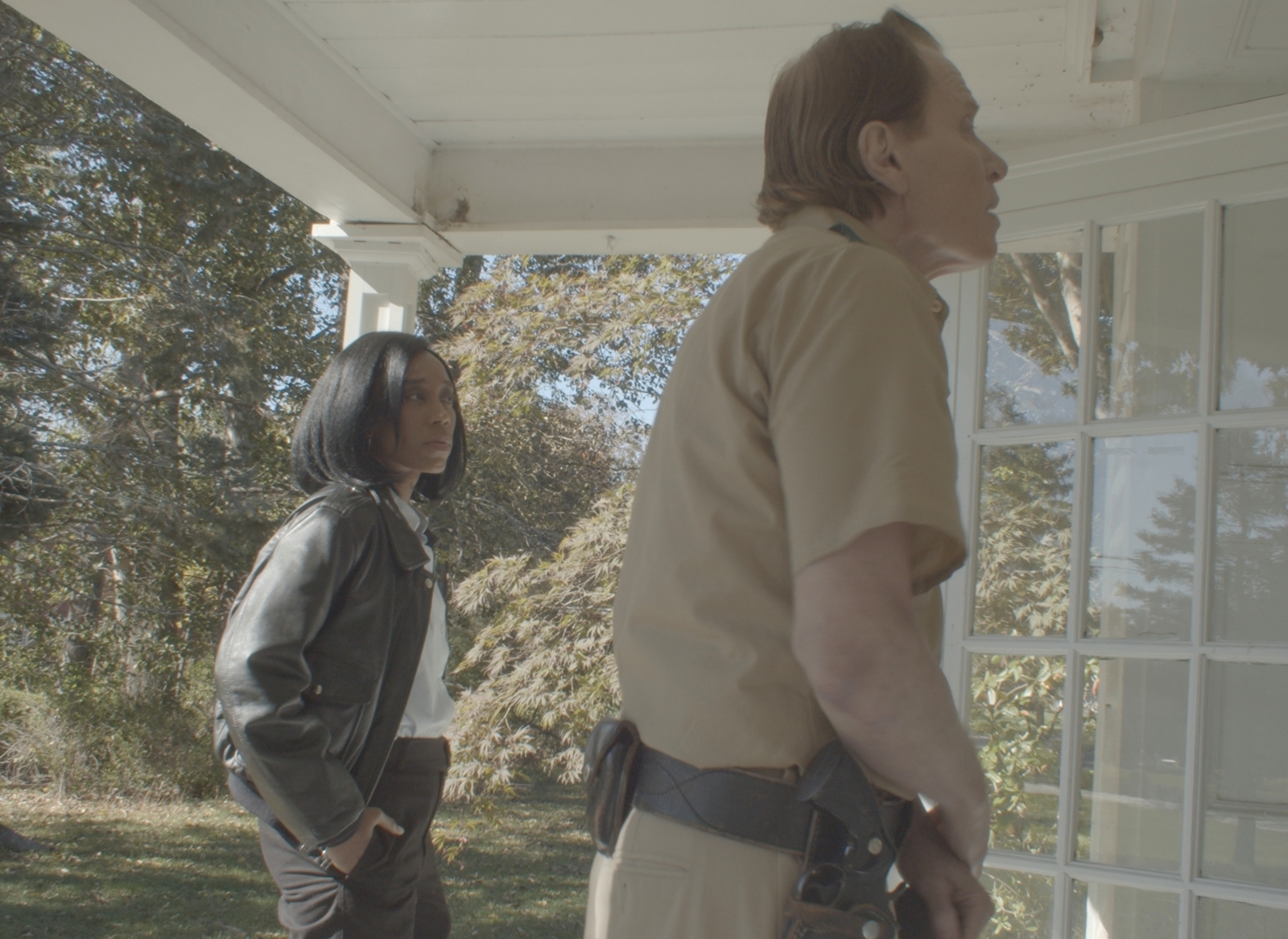 Movie screengrab side profile of a male policeman and woman at the door of a house
