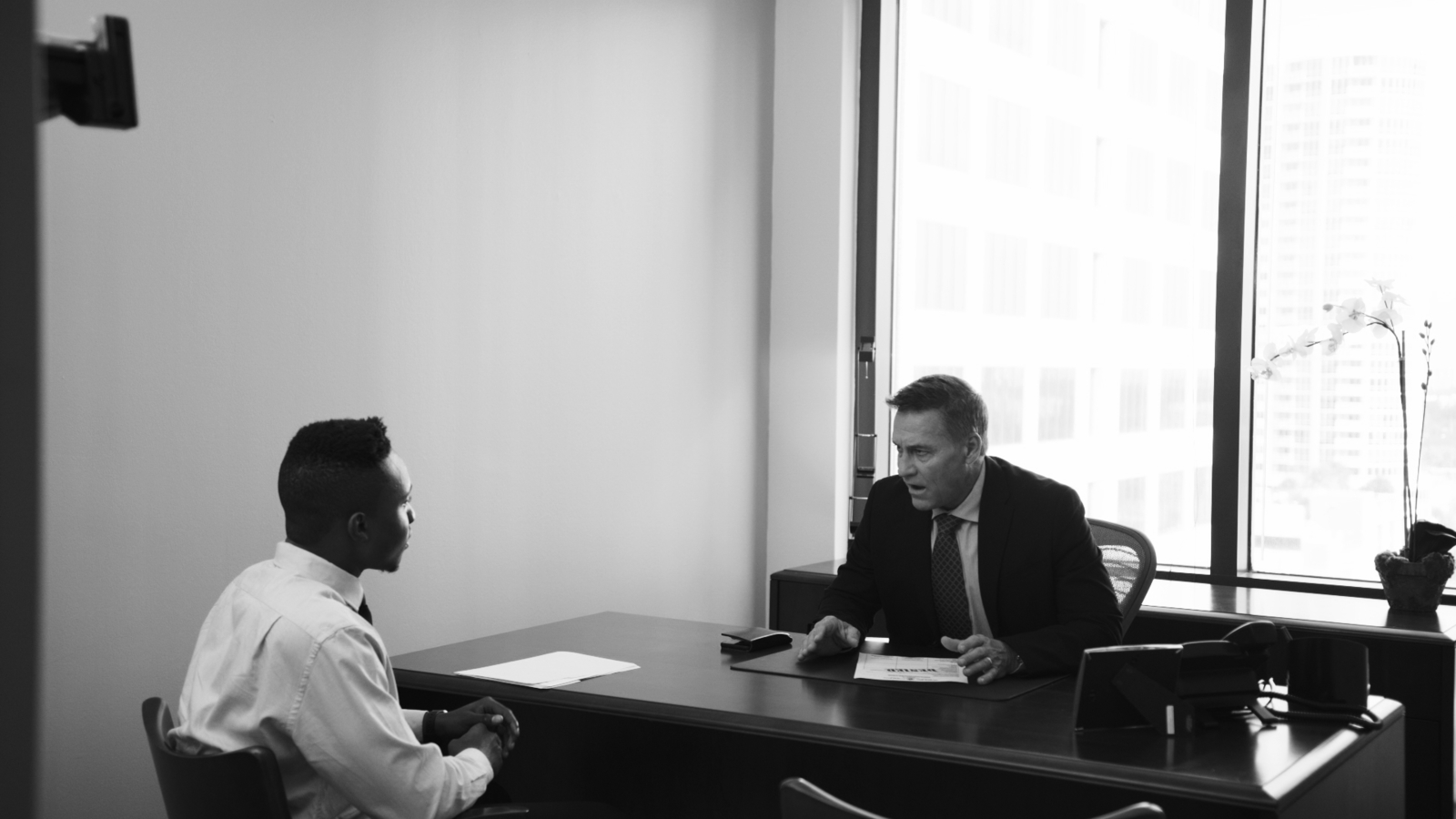 The Different Types of Corporate Videos and When to Use Them Black and white of man talking to young African American man in an office