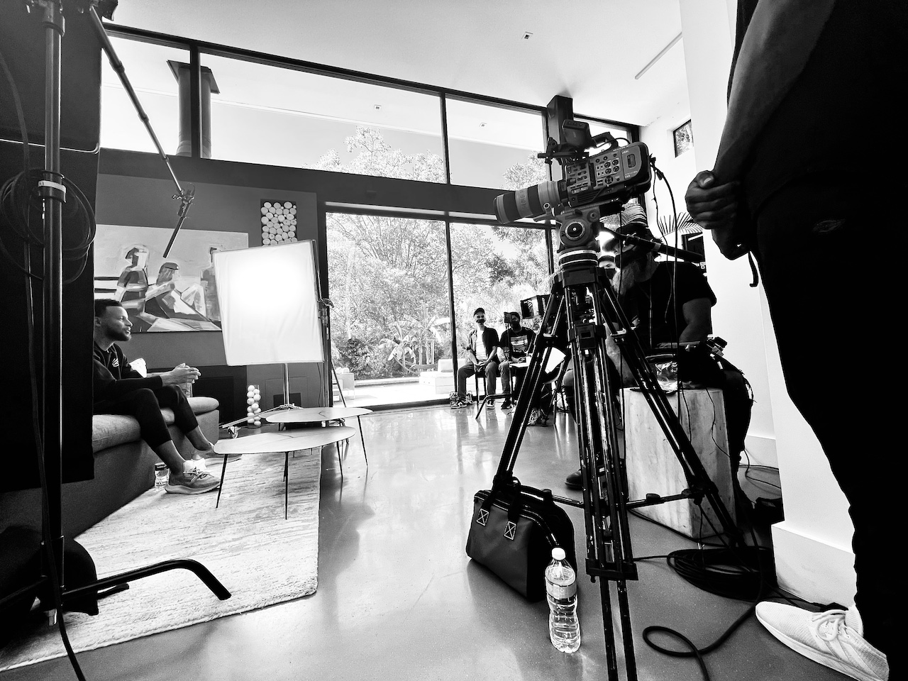 Documentary Film Production BlackPopBTS Steph Curry by CI Studios with black and white of him on set sitting on a couch with tables near him along with crew and equipment