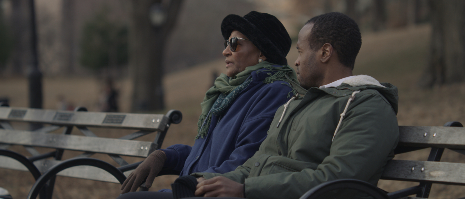 Character Development Side view of African American man and woman sitting on a bench talking