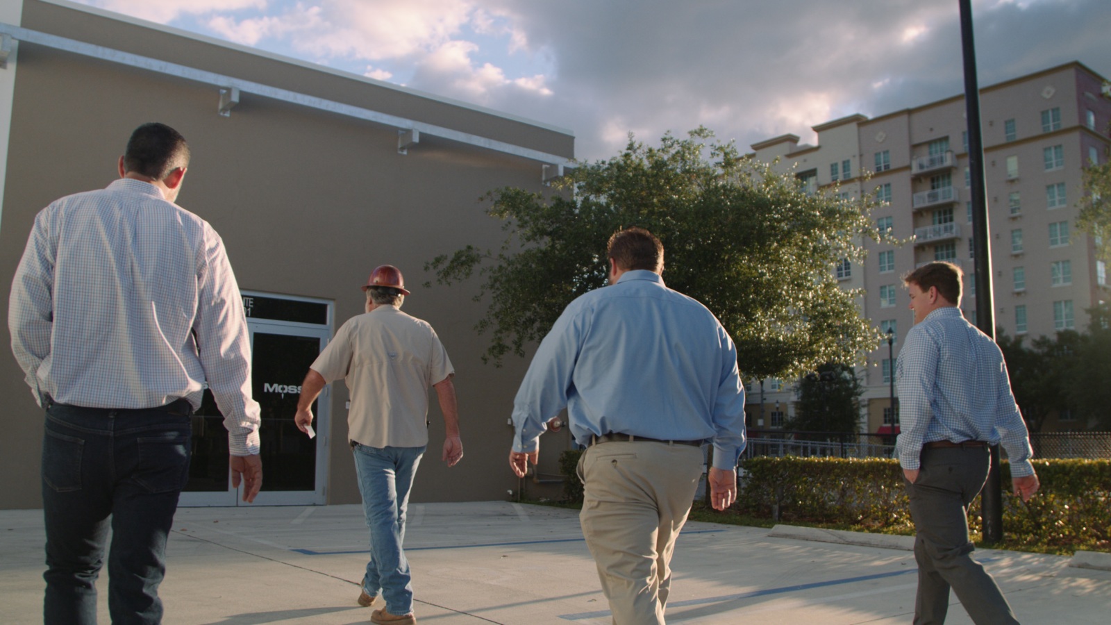 View from behind of four men walking towards a Moss Construction building