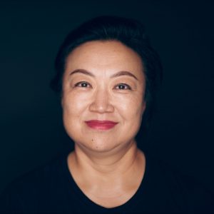 May Wong Headshot Against Black Backdrop