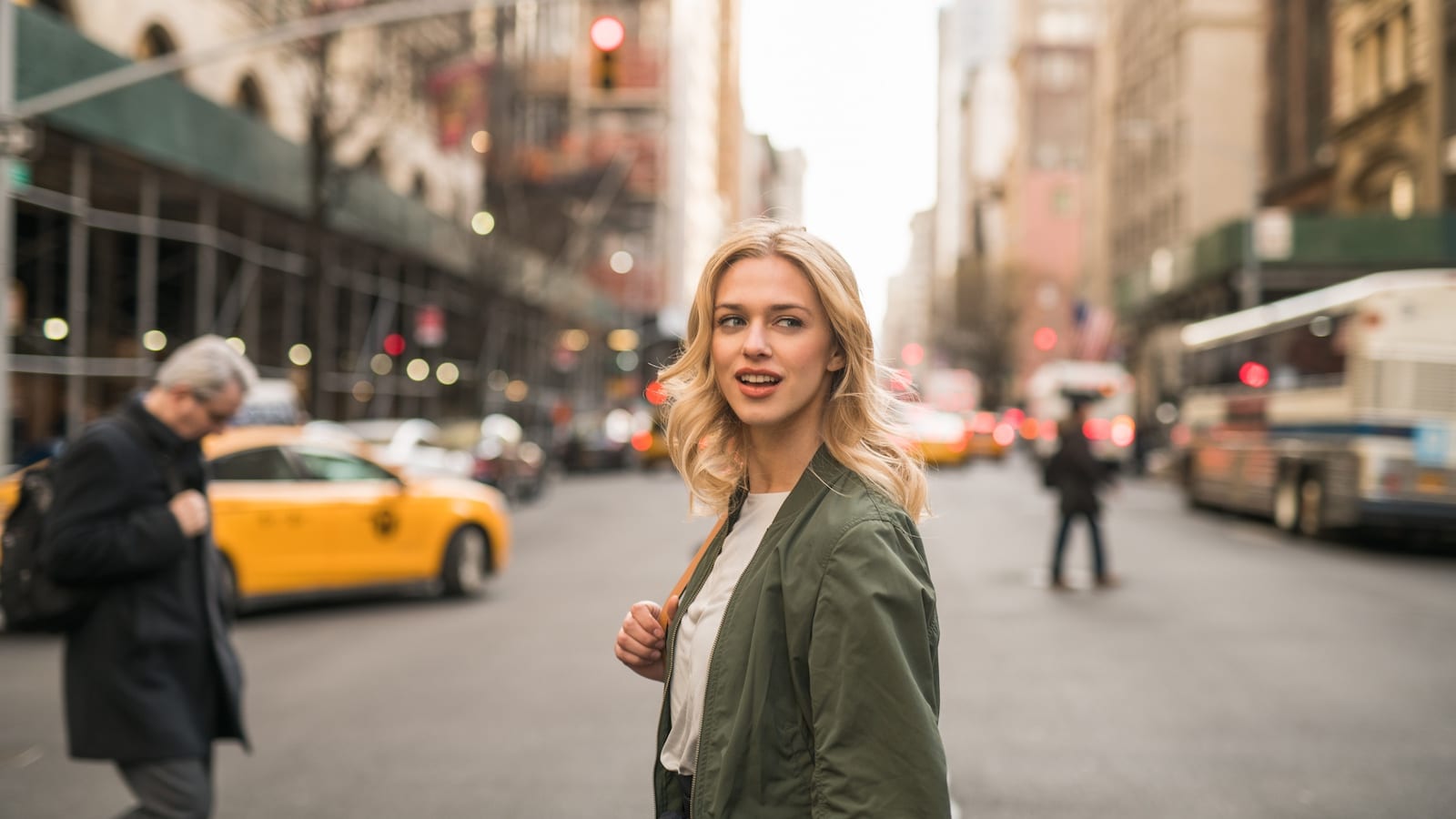 Side profile of model with long blond hair crossing a street in the city
